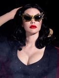 Heather Clarke wearing the Vampira Bat Glasses in Gold/Black in a foggy room.