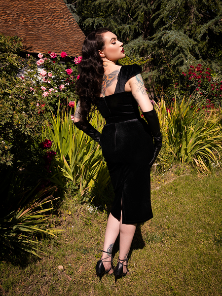 Micheline Pitt turned away from the camera to show off the back of the Baudelaire Wiggle Dress in Black.