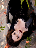 While laying down on a stone seated area, Micheline Pitt shows off the Baudelaire Wiggle Dress in Black.