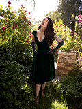 The Baudelaire Swing Dress in Hunter Green worn by Micheline Pitt she she tucks her hands into the side pockets.