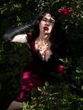 Micheline Pitt holding her hand up to her brow while modeling the  Baudelaire Wiggle Dress in Oxblood from gothic fashion brand La Femme en Noir.