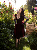 Full length image of the Baudelaire Swing Dress in Oxblood being worn by Micheline Pitt.