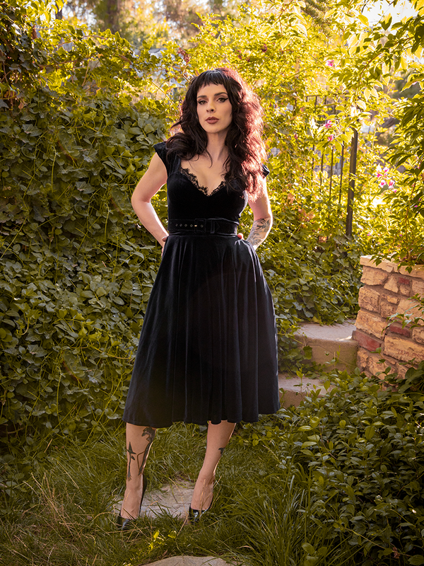 Stephanie tucking her hands into the pockets of her Baudelaire Swing Dress in Black from goth dress company La Femme en Noir.