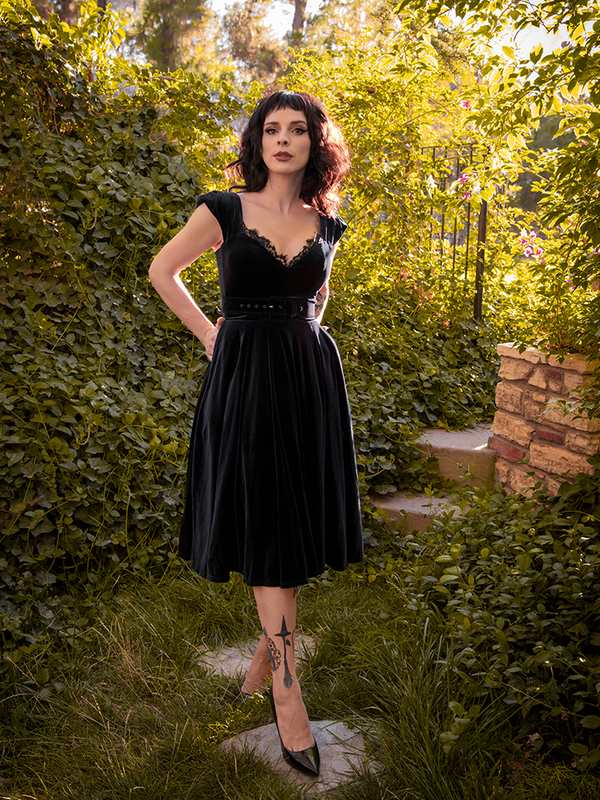 Tucking her hands into the pockets of her Baudelaire Swing Dress in Black from La Femme en Noir.