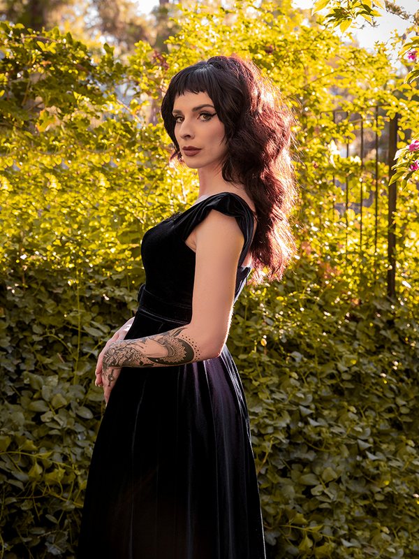 Profile shot of Stephanie as she turns toward the camera while wearing the Baudelaire Swing Dress in Black from La Femme en Noir.