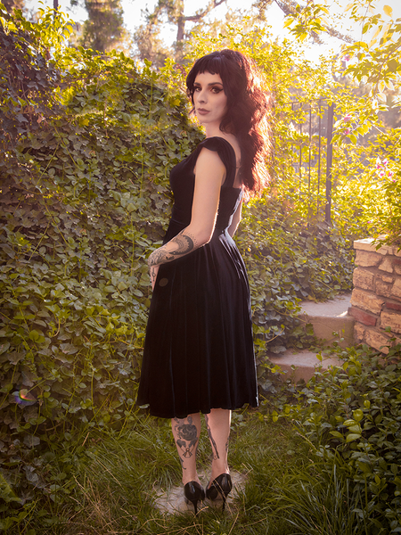 Stephanie turned to the side while wearing the Baudelaire Swing Dress in Black to show off her profile.