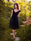 Stephanie seductively looking into the camera while modeling the Baudelaire Swing Dress in Midnight Blue from gothic glamour clothing company La Femme en Noir.