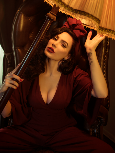 Micheline Pitt, tilting a lamp to her face, models the Bauhaus top in oxblood.