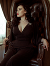Rachel sits on a dark colored leather chair while modeling the Bauhaus top in black from La Femme En Noir.
