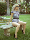 Lynh is sitting in a garden while modeling the Betelgeuse swimsuit by La Femme En Noir.