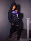 Full length shot of female model wearing the Ghost Sweatshirt paired with ripped black jeans and black ankle boots.