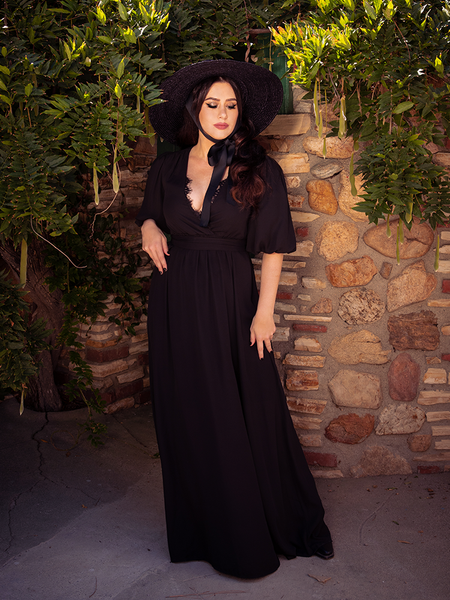 Donning the Odyssey Maxi Dress in Black from La Femme en Noir, Ashley peers into the distance.