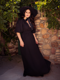 Ashley gazes into the horizon, clad in the Odyssey Maxi Dress in Black from La Femme en Noir, a gothic fashion brand.