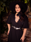 Wearing the Odyssey Maxi Dress in Black by La Femme en Noir, Ashley closes her eyes..
