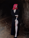 Full body length picture of model Mackenzie thrusting her leg out while wearing the Black Widow Wrap Gown in Solid Black from La Femme en Noir.