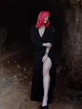 Full body length picture of model Mackenzie thrusting her leg out while wearing the Black Widow Wrap Gown in Solid Black from La Femme en Noir.