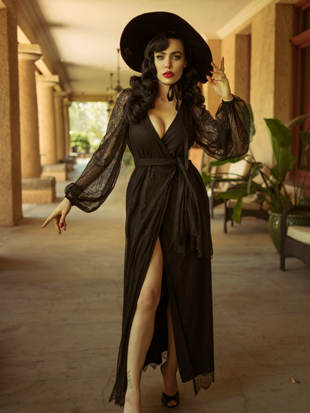 Micheline Pitt modeling the Black Widow Wrap Gown in Black Lace paired with a black sunhat.