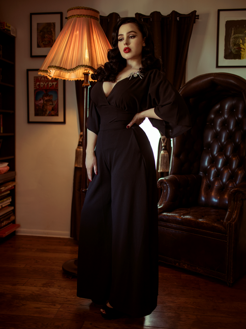 Rachel Sedory with her hand on her hip and another resting at her side models the Black Widow Palazzo Pants in Black from La Femme en Noir. 