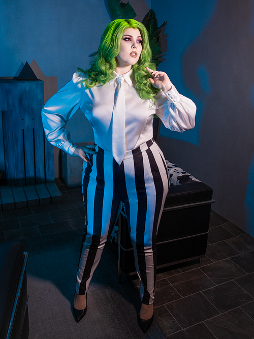 Full length photo of model posing in the Bowie Blouse w/Matching Tie in White Charmeuse with matching black and white striped pants. 