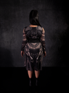 A full length photo of Jyoti modeling the back of the Corset Belt in Black Faux Leather by La Femme En Noir.