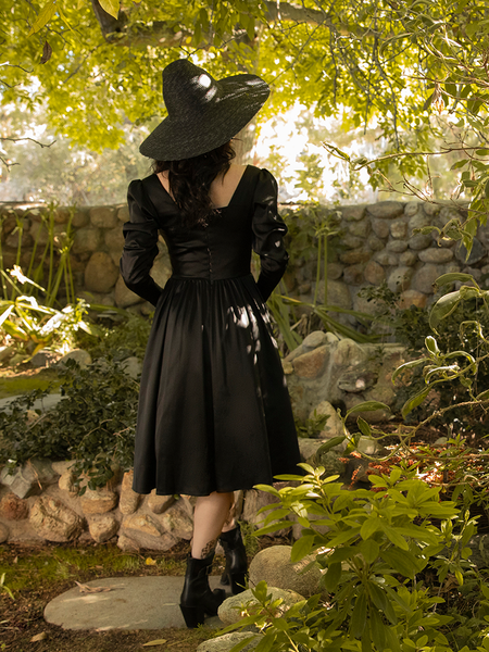 The Cottage Witch Dress in Japanese Black Satin shot from the back while being worn by La Femme en Noir model Stephanie. 