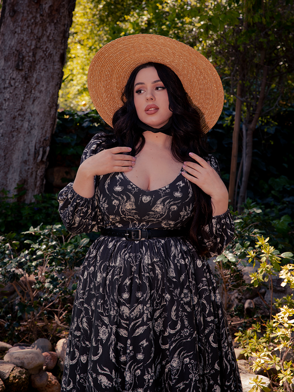 A stunning brunette figure adorns the haunting forest backdrop, clad in the exquisite Dark Forest Dress, a captivating creation by La Femme en Noir, the Gothic dress aficionado.