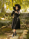 Placing her hands in the pockets of her Cottage Witch Dress in Japanese Black Satin, Stephanie models the latest gothic dress from La Femme en Noir.