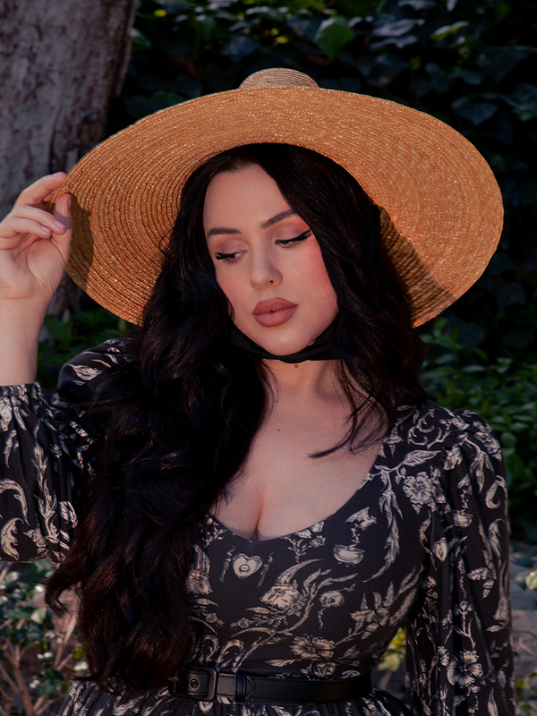 The dark haired female model looks mesmerizing in her gothic clothing outfit that's perfectly accented by La Femme en Noir's Cottage Witch Hat in Natural.