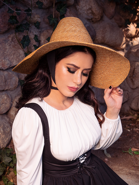 The Cottage Witch Hat in Natural from La Femme en Noir complements the dark haired female model's gothic clothing outfit, making her look stunning.