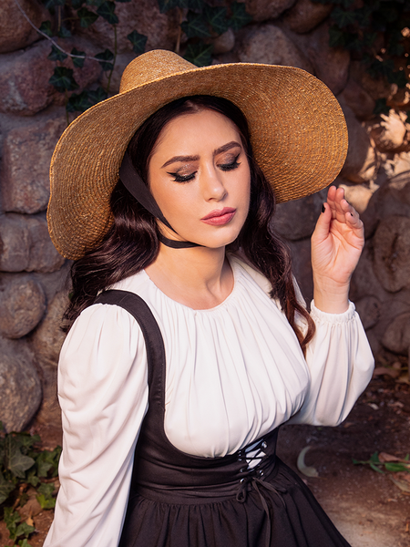 La Femme en Noir's Cottage Witch Hat in Natural is a perfect accessory that enhances the stunning gothic clothing outfit worn by the dark haired female model.