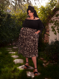 The alluring female model effortlessly showcases the Gothic Tales Skirt in Cottage Witch Toile Print from the gothic clothing brand La Femme en Noir.