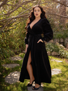 Rachel Sedory standing in a garden while wearing a black gothic dress.