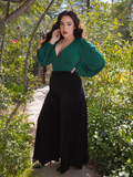 Rachel Sedory fiercely posing with one hand on her hip while turned to the side, while sporting the Crawford Palazzo Pants in Black.