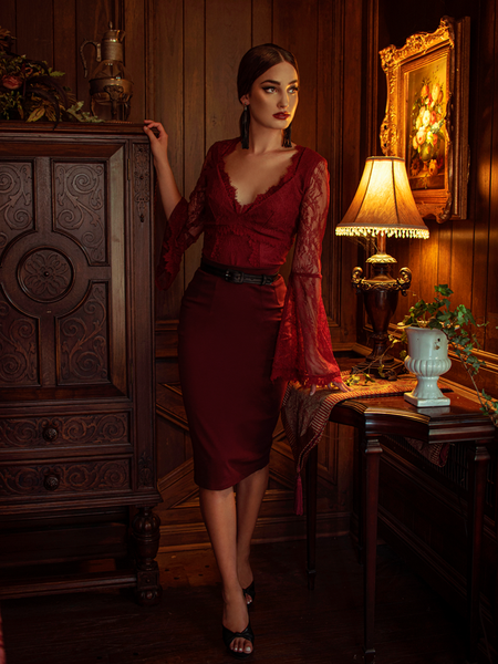 Aliza standing in a dimly lit room modeling the Vamp pencil skirt in oxblood.