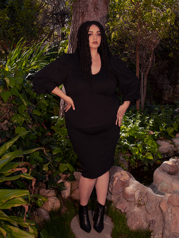 Amidst the breathtaking beauty of a wooded forest area, a stunning brunette model effortlessly flaunts the Black Dark Forest Blouse. Indulge in the gothic elegance of La Femme en Noir.
