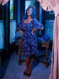 Vanessa posing in the foyer of a Victorian house with her hands on her hips and wearing Tim Burton's CORPSE BRIDE™ Butterfly Babydoll Dress in Dusk Blue.
