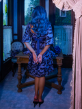 Full length shot of turned away from the camera to show off the back of the Tim Burton's CORPSE BRIDE™ Butterfly Babydoll Dress in Dusk Blue from gothic glamour clothing company La Femme en Noir.