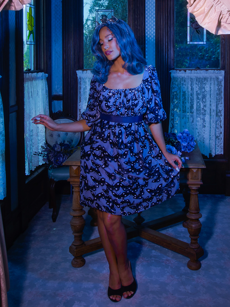 Vanessa gently pulls on the skirt portion of her Tim Burton's CORPSE BRIDE™ Butterfly Babydoll Dress in Dusk Blue to show off the gorgeous butterfly print.