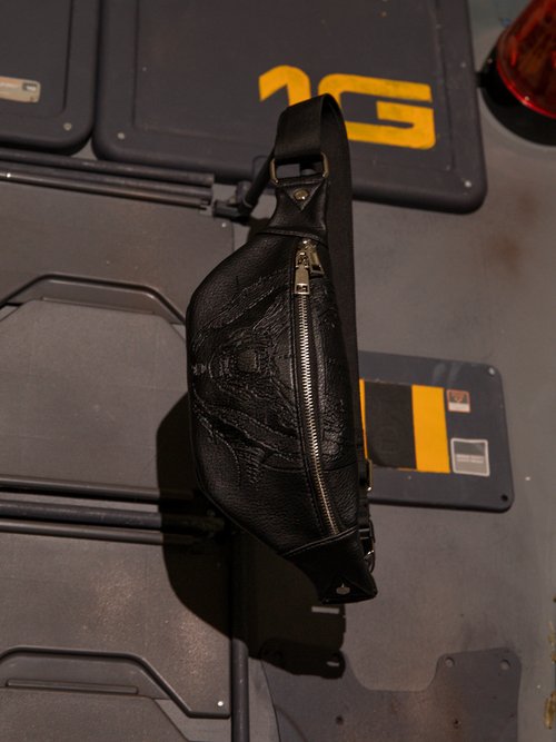 The ALIEN Xenomorph Hip Bag hanging from a metal rod protruding from the wall.