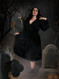 Full length shot of Rachel standing in a scary cemetery scene to show off the Sleepy Hollow Gothic Tales Velour Skirt in Black from La Femme en Noir.