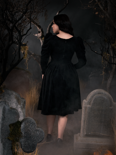 Rachel Sedory showing off the back of her gothic dress while standing in a spooky graveyard.