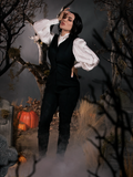 Micheline Pitt standing to the side with one hand on her hip and the other pressed to her head wears a Sleepy Hollw inspired outfit including the Sleepy Hollow Ichabod Pants in Black.