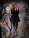 A mysterious figure holds the Sleepy Hollow Pumpkin Bag in front of their face while standing amongst fog covered tombstones.