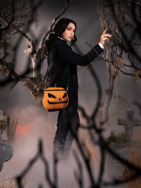 Micheline Pitt, dressed as Ichabod Crane, is turned to the side to show off the Sleepy Hollow Pumpkin Bag.