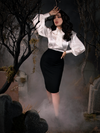Full length shot of Micheline Pitt standing in a foggy cemetery while wearing the Sleepy Hollow Ichabod Pencil Skirt in Black. 
