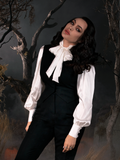 Micheline Pitt standing and slight slouched over with her head resting on her shoulder models the Victorian Blouse in Ivory - a new addition to the line of gothic retro clothing from La Femme en Noir.