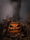 The Sleepy Hollow Pumpkin Bag photographed in front of a fog covered tree sitting on a bed of old leaves. 