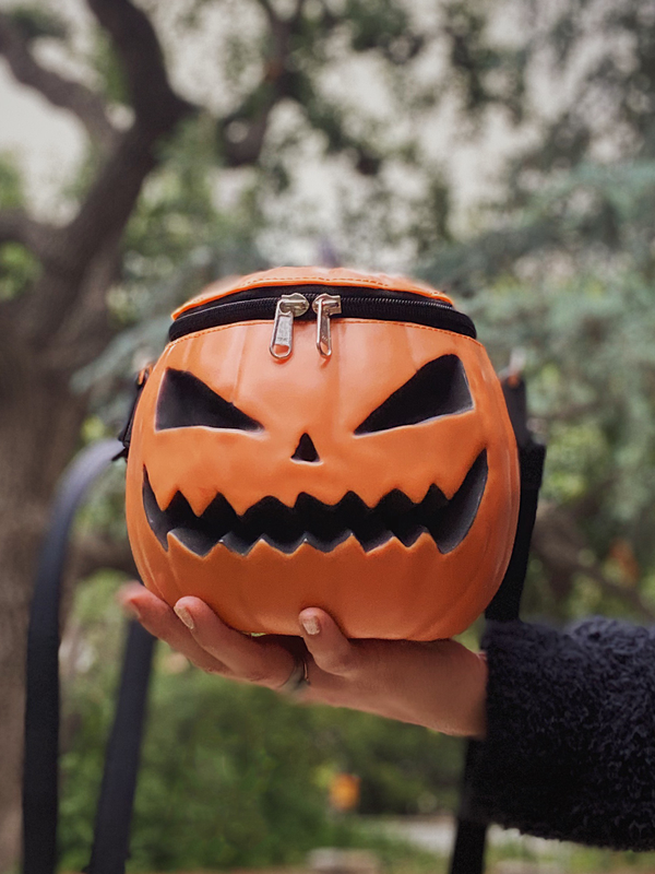 The Sleepy Hollow Baby Pumpkin Bag being held in the palm of a model's hand.