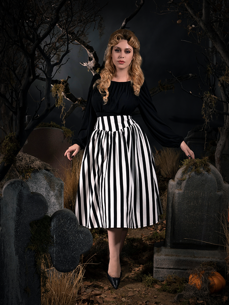 Linda, resting her left hand of a tombstone, poses in a gothic style outfit including the Sleepy Hollow The Katrina Skirt in Black and White.