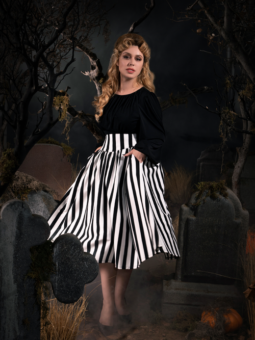 Full length shot of Linda in a gothic retro clothing outfit standing amongst tombstones in a graveyard setting.